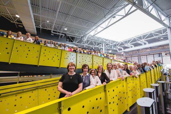 Group photo of the women of the Mary Free Bed Guild lined up on yellow ramp at Mary Free Bed YMCA