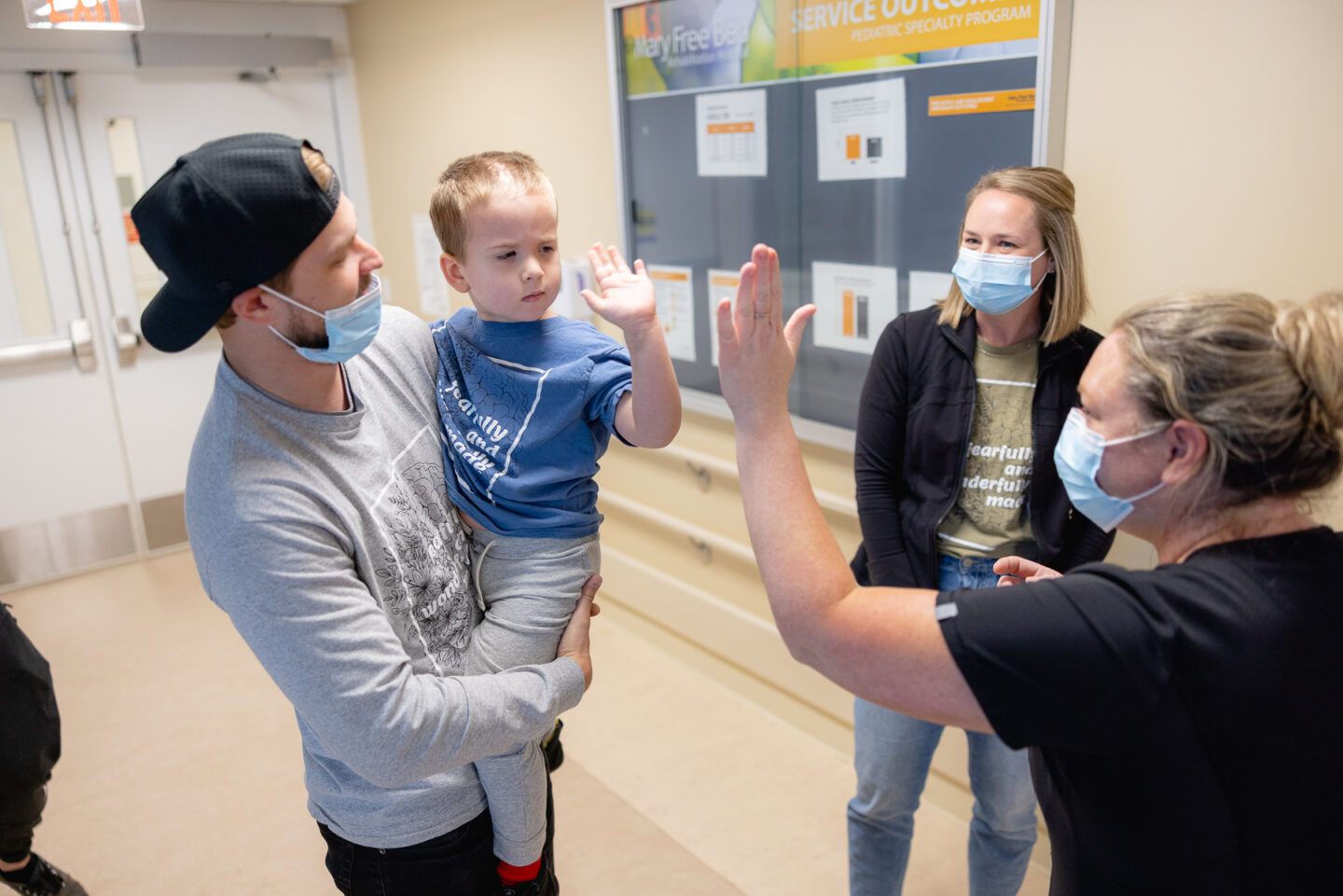 High-five gesture between pediatric patient and nurse wearing a covid face mask