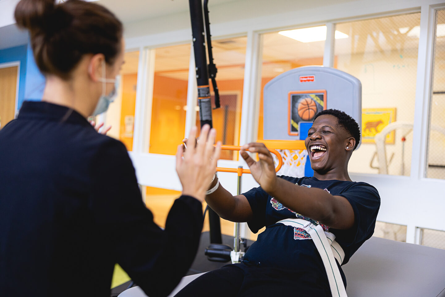 A young man laughing during a therapy session in a Mary Free Bed gym