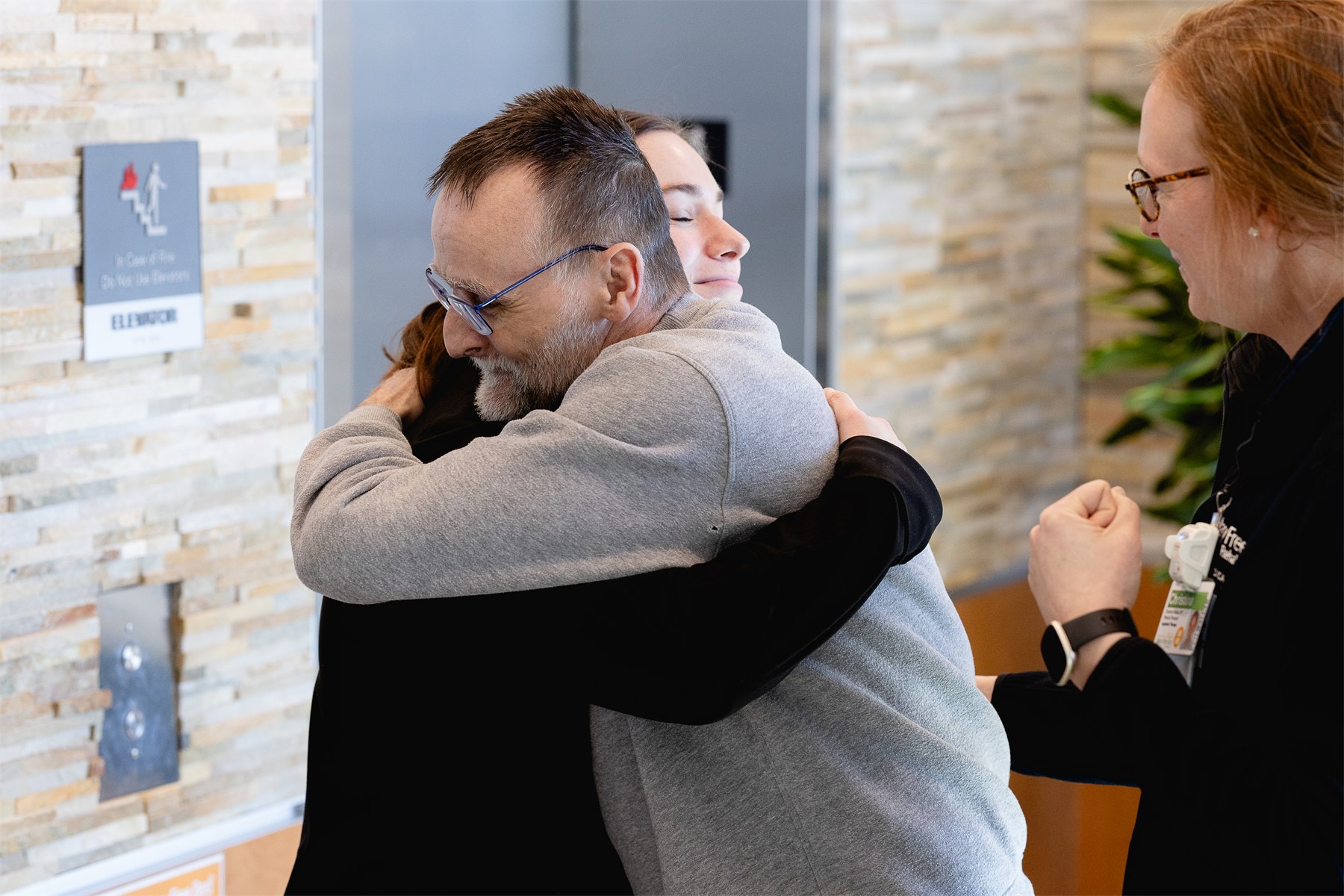 A patient and a Mary Free Bed team member embracing while a colleague celebrates beside them