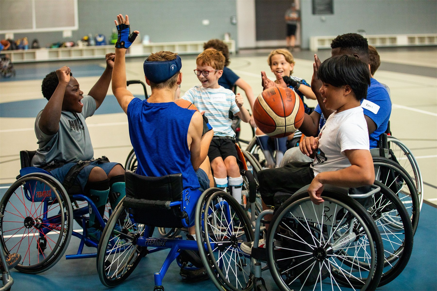 Children in sport wheelchairs celebrating together on the court at a Mary Free Bed sports camp