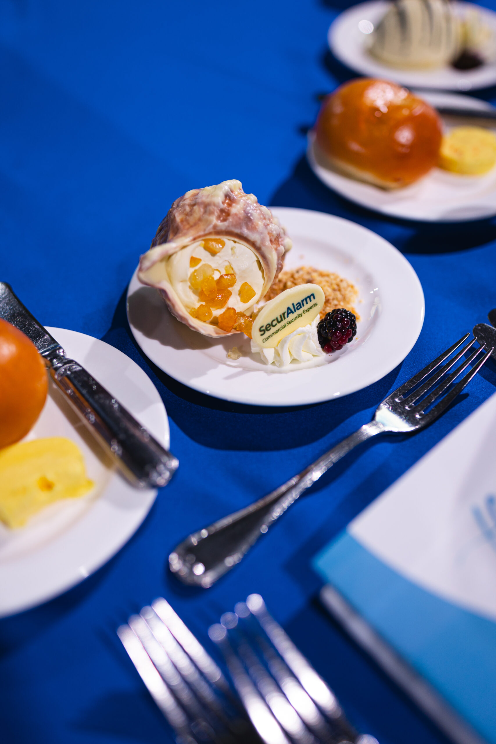 A plated dessert on a blue tablecloth marked with the SecurAlarm logo
