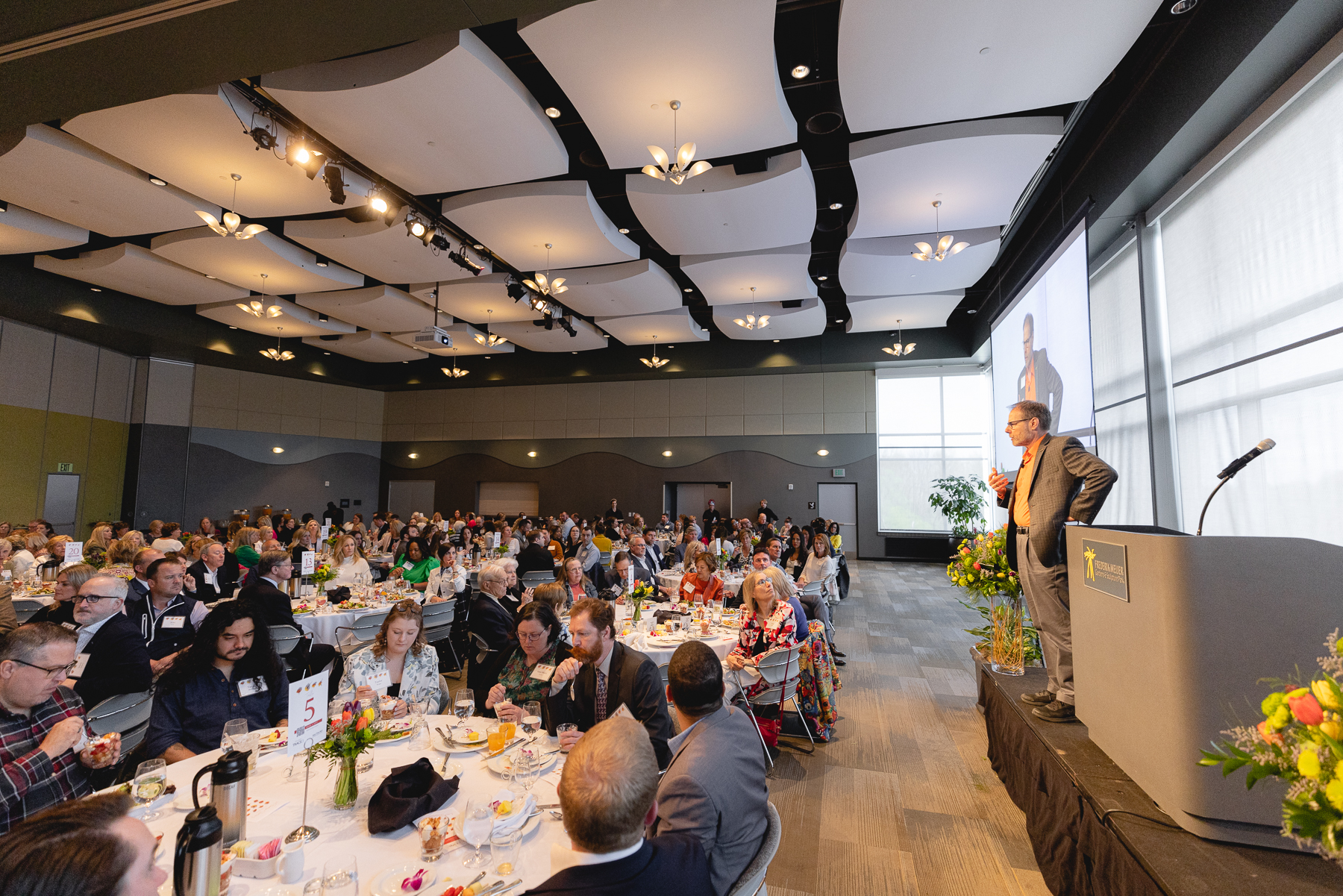 Guests seated at round tables during a Foundation luncheon while a speaker addresses the room