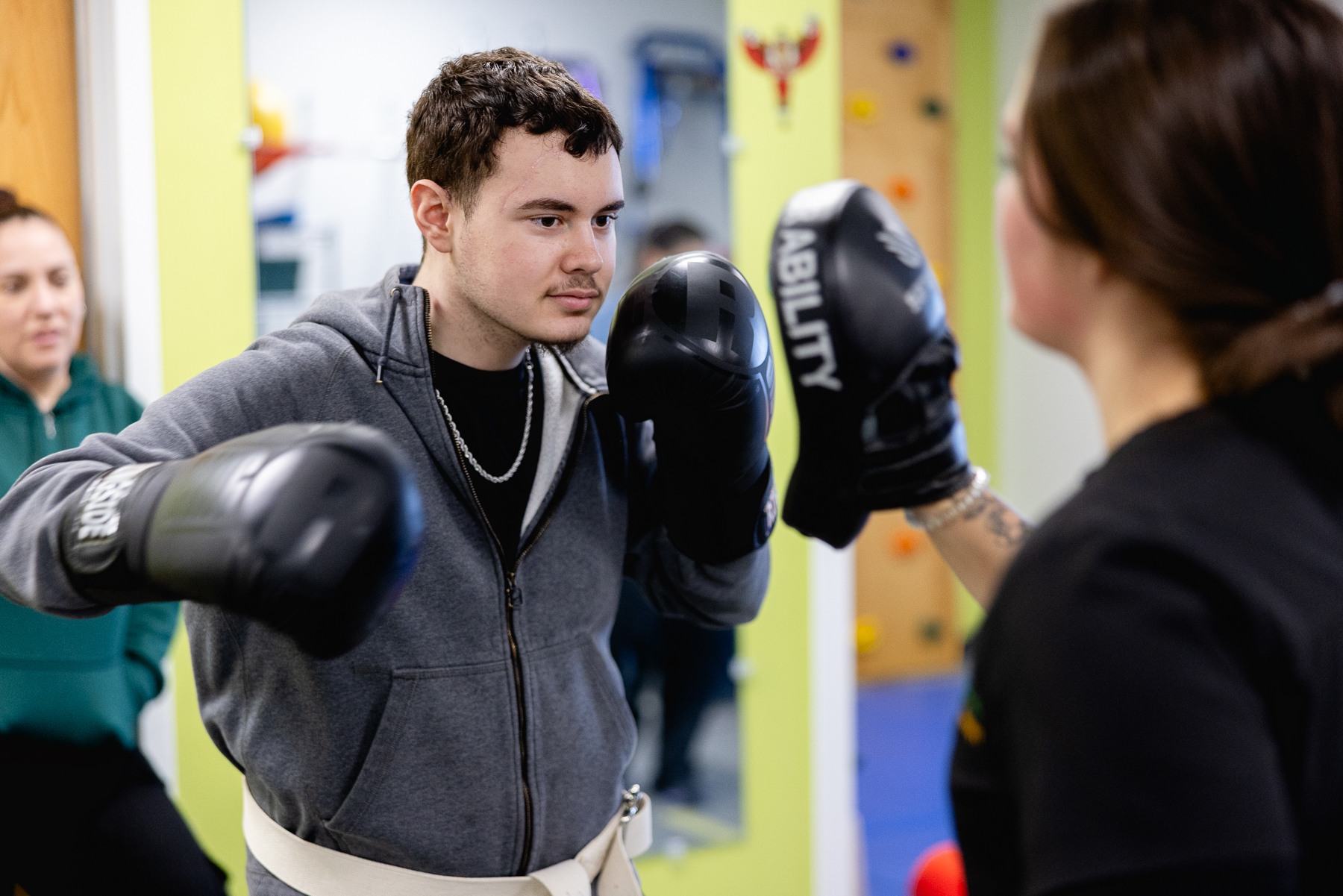 Miguel practicing boxing with padded gloves during a therapy session