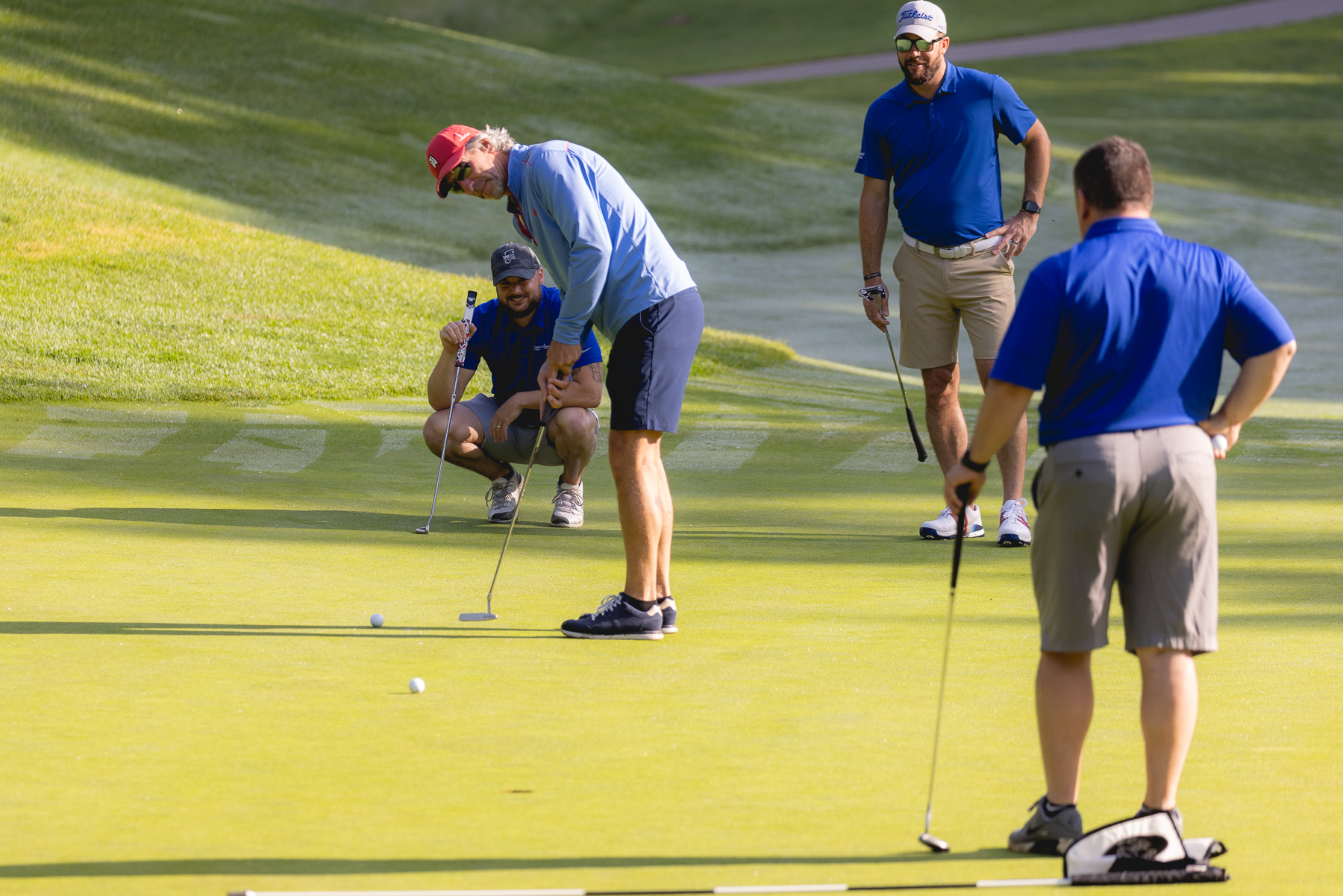 Golfers lining up a putt on the green at the Mary Free Bed Open