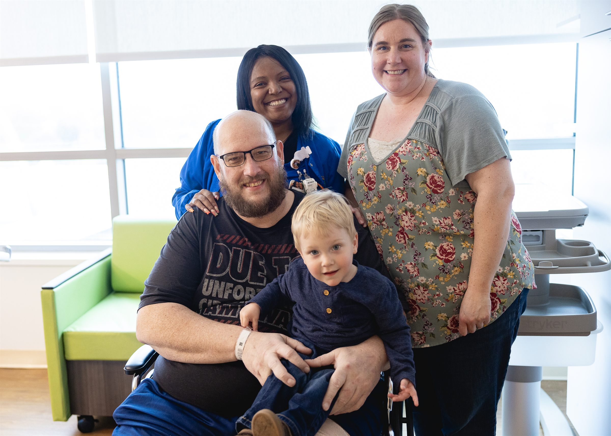 A Mary Free Bed patient with his young son, family and care team celebrating his therapy graduation