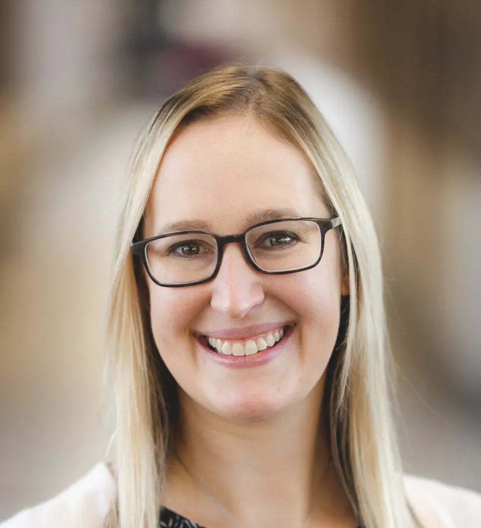 Smiling Mary Free Bed pediatric specialist with blonde hair and glasses wearing a patterned top and pink cardigan