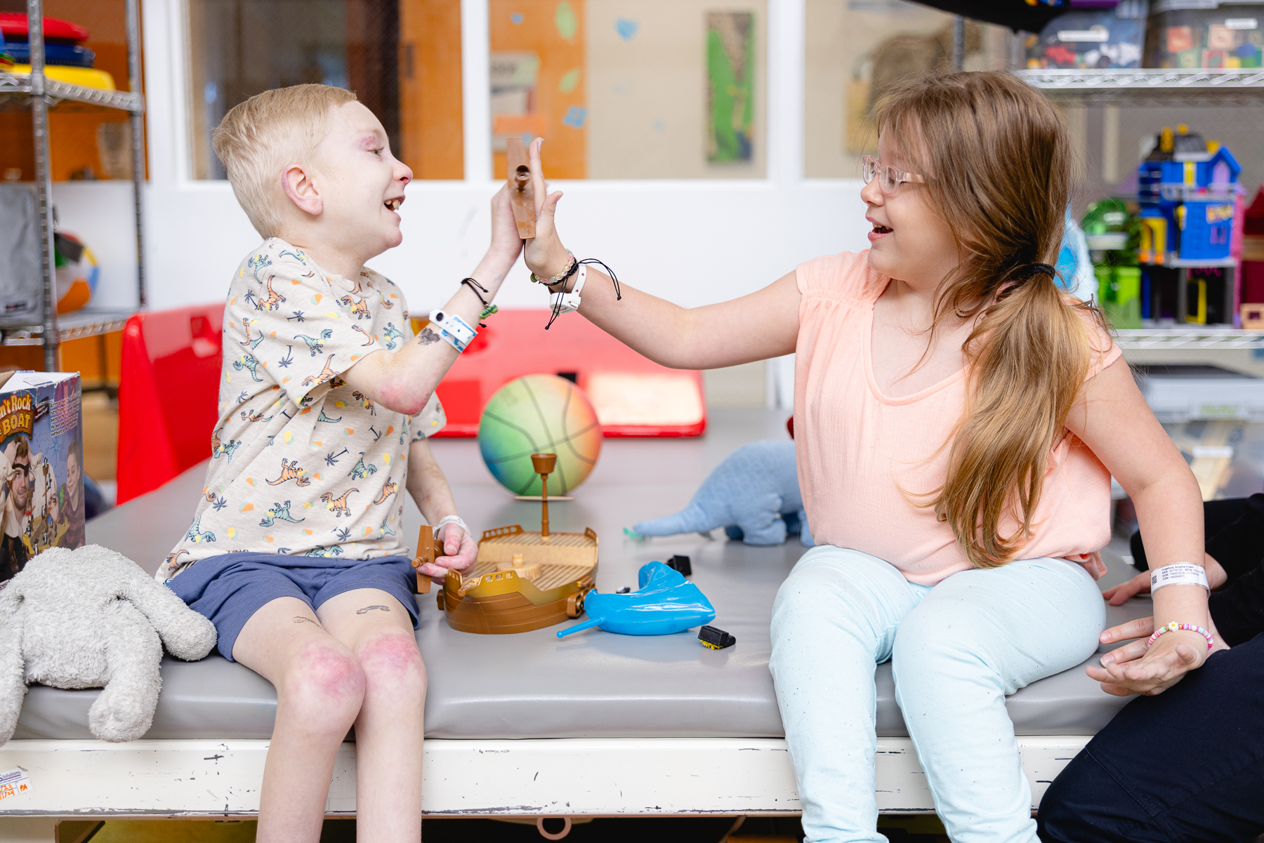 Pediatric occupational therapist working with a young child during a therapy session in a rehabilitation clinic, engaging in interactive play with wooden toys and musical instruments to support developmental and motor skill activities