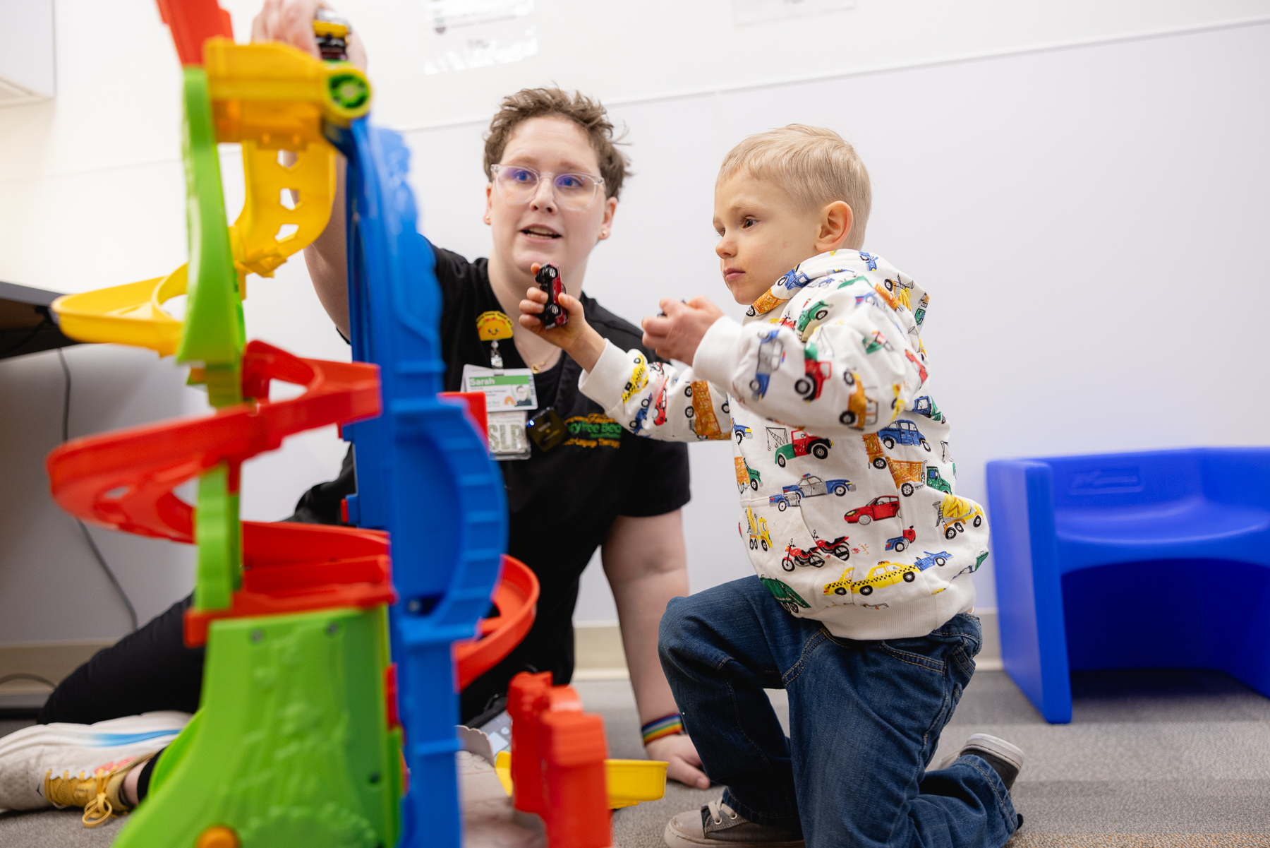 Mary Free Bed pediatric therapist engaging a young child in play therapy using a colorful toy car ramp