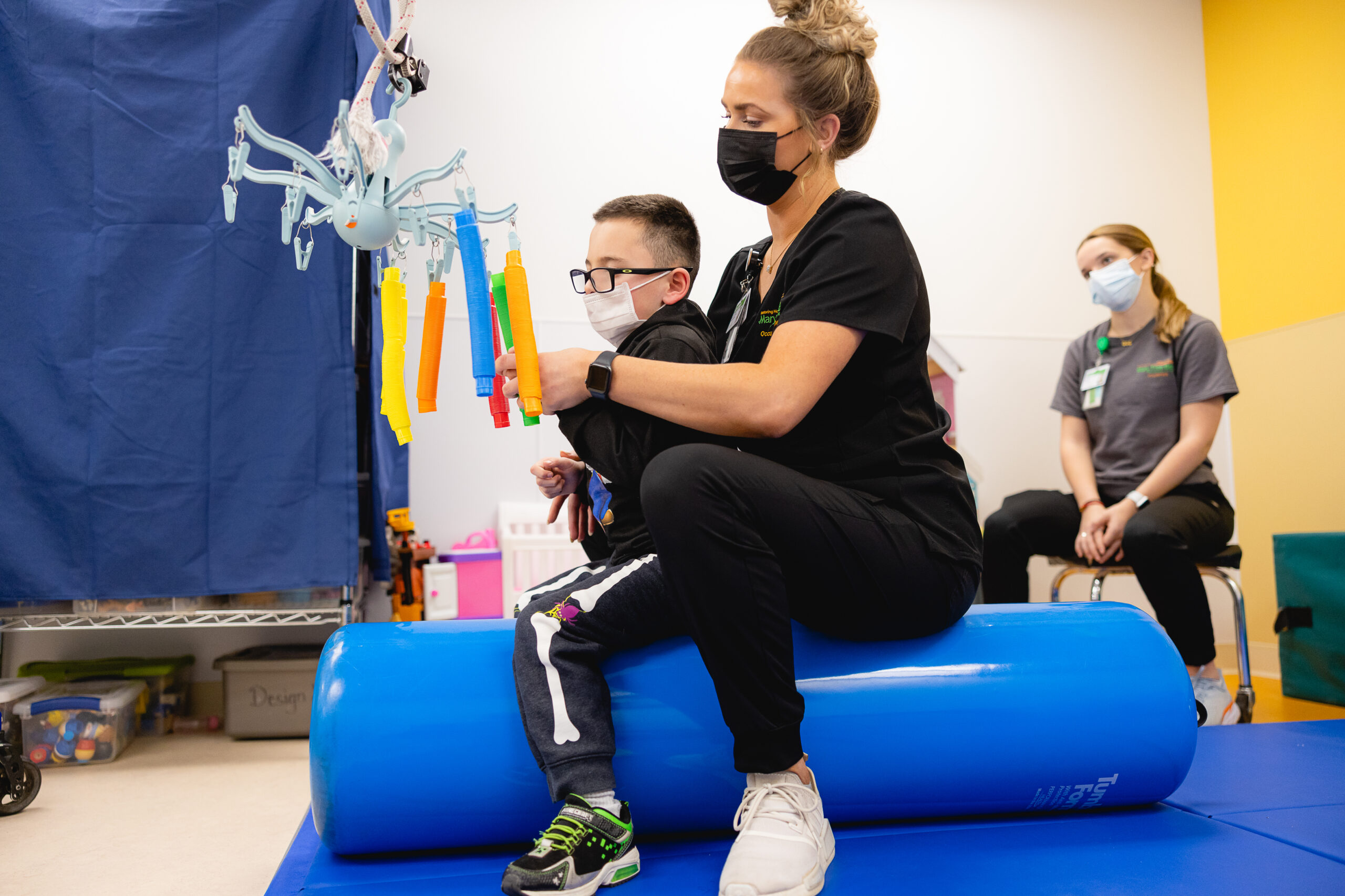 A therapist helping a pediatric patient through a therapy exercise.