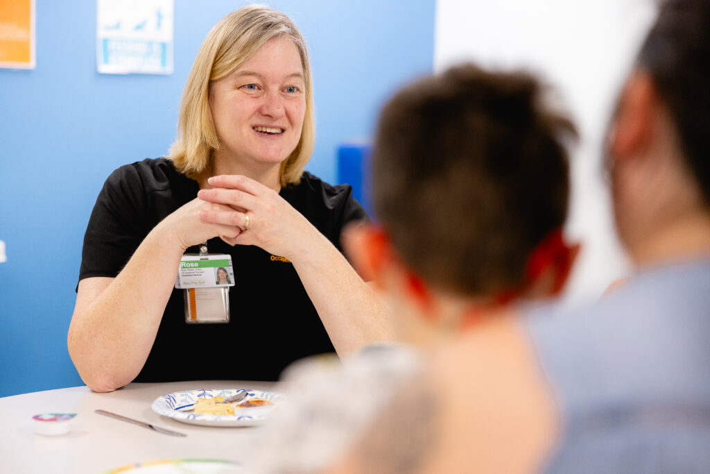An occupational therapist talking with a pediatric patient and a parent.