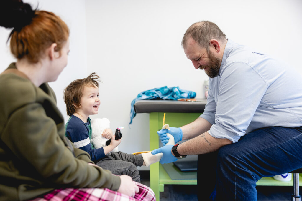 An orthotist helps test fit an orthosis with a pediatric patient