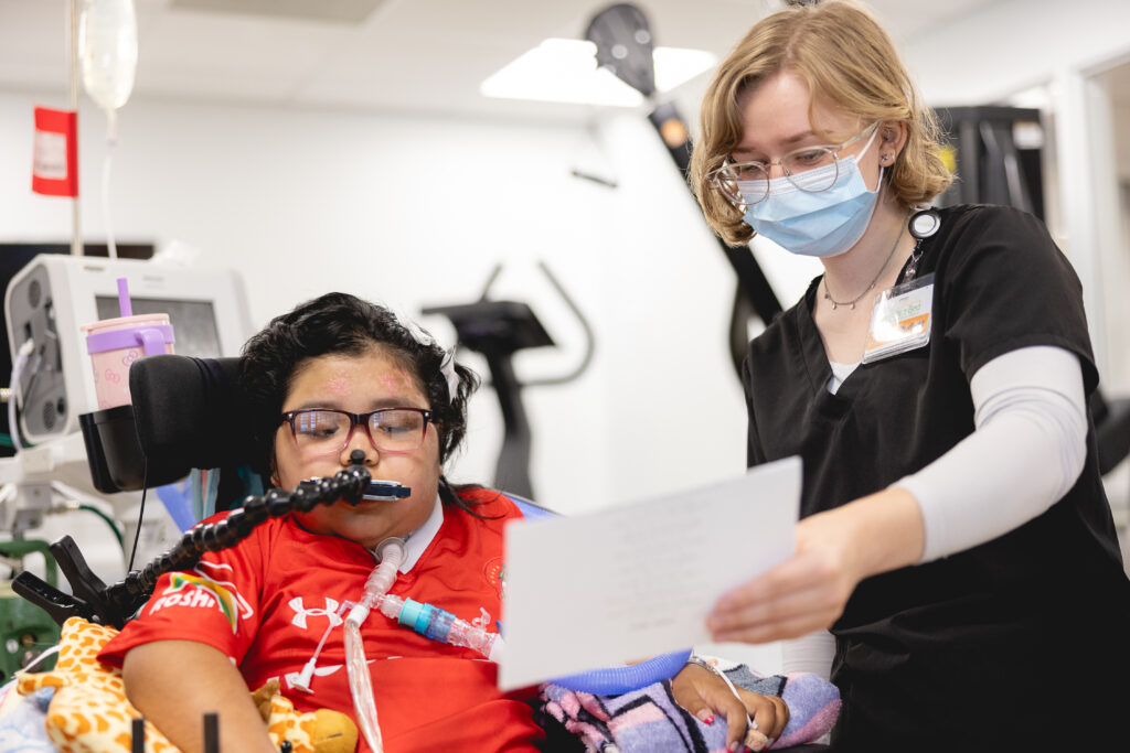 A respiratory therapist holding a set of lyrics up for a patient to sing.