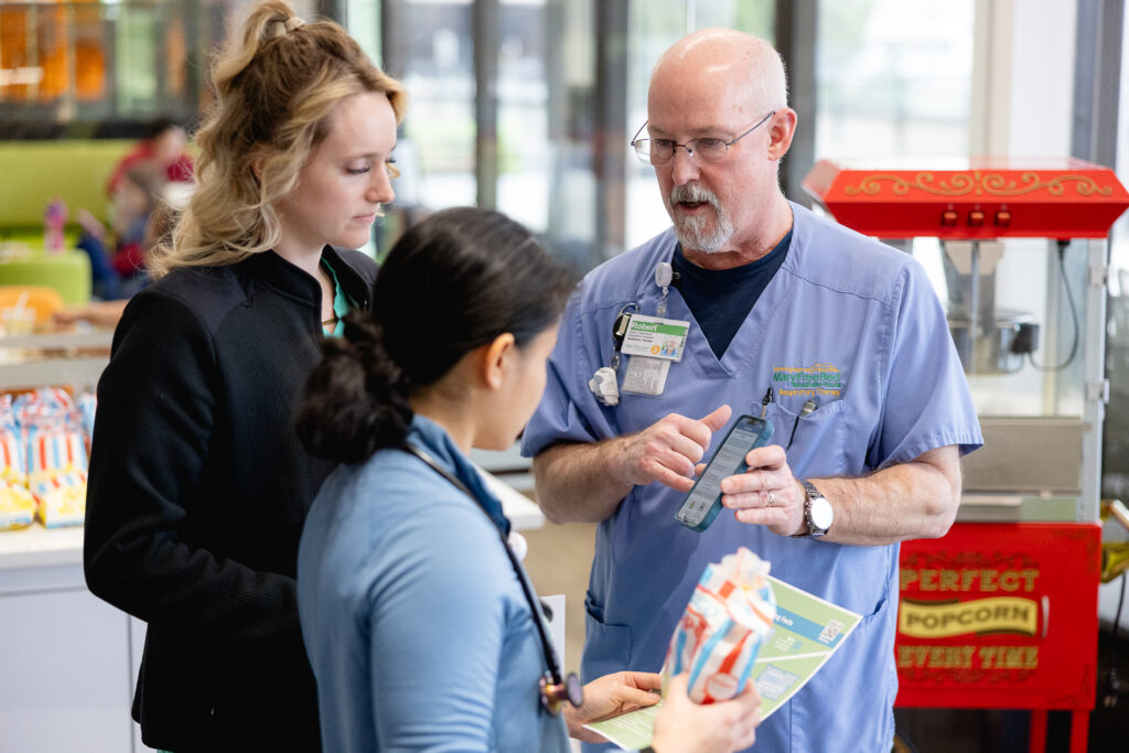 A respiratory therapist showing other clinicians information on a phone.