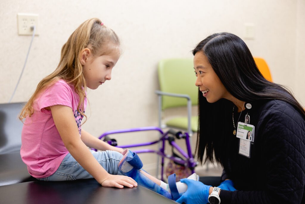An orthotist fitting an AFO with a pediatric patient