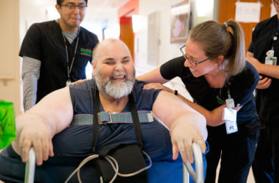 Travis Laws smiles while receiving support from physical therapists during his rehabilitation at Mary Free Bed.