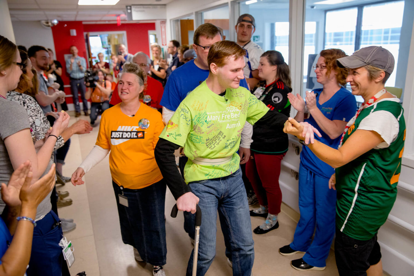 A Mary Free Bed patient receiving congratulations and high-fives from staff and supporters.