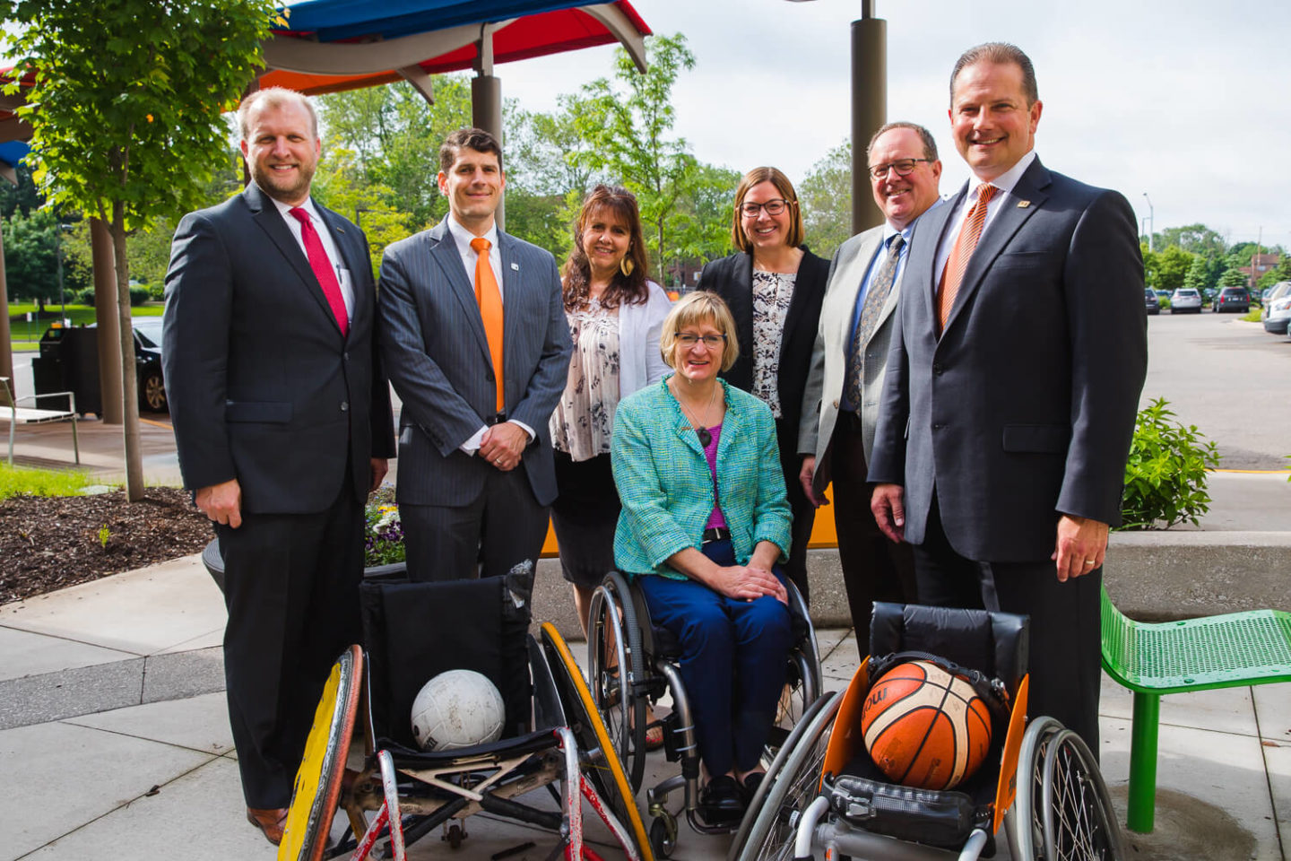 Representatives from Fifth Third Bank and Mary Free Bed standing beside adaptive sports wheelchairs equipped with sports equipment.