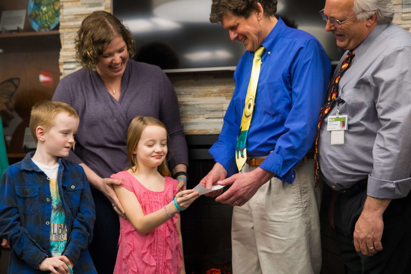 Devyn hands a check to a Mary Free Bed representative, while her family and another staff member look on with smiles.