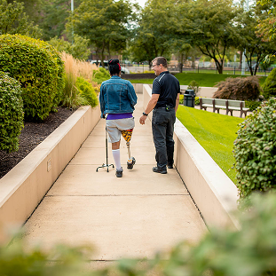 Brain Injury 41 patient walking outside with prosthetic leg and cane