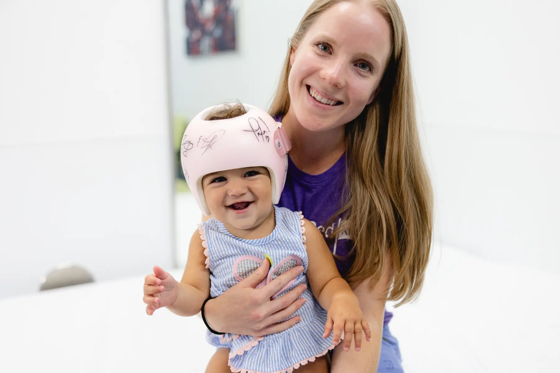 A Mary Free Bed worker holding a baby wearing a cranial remolding helmet.