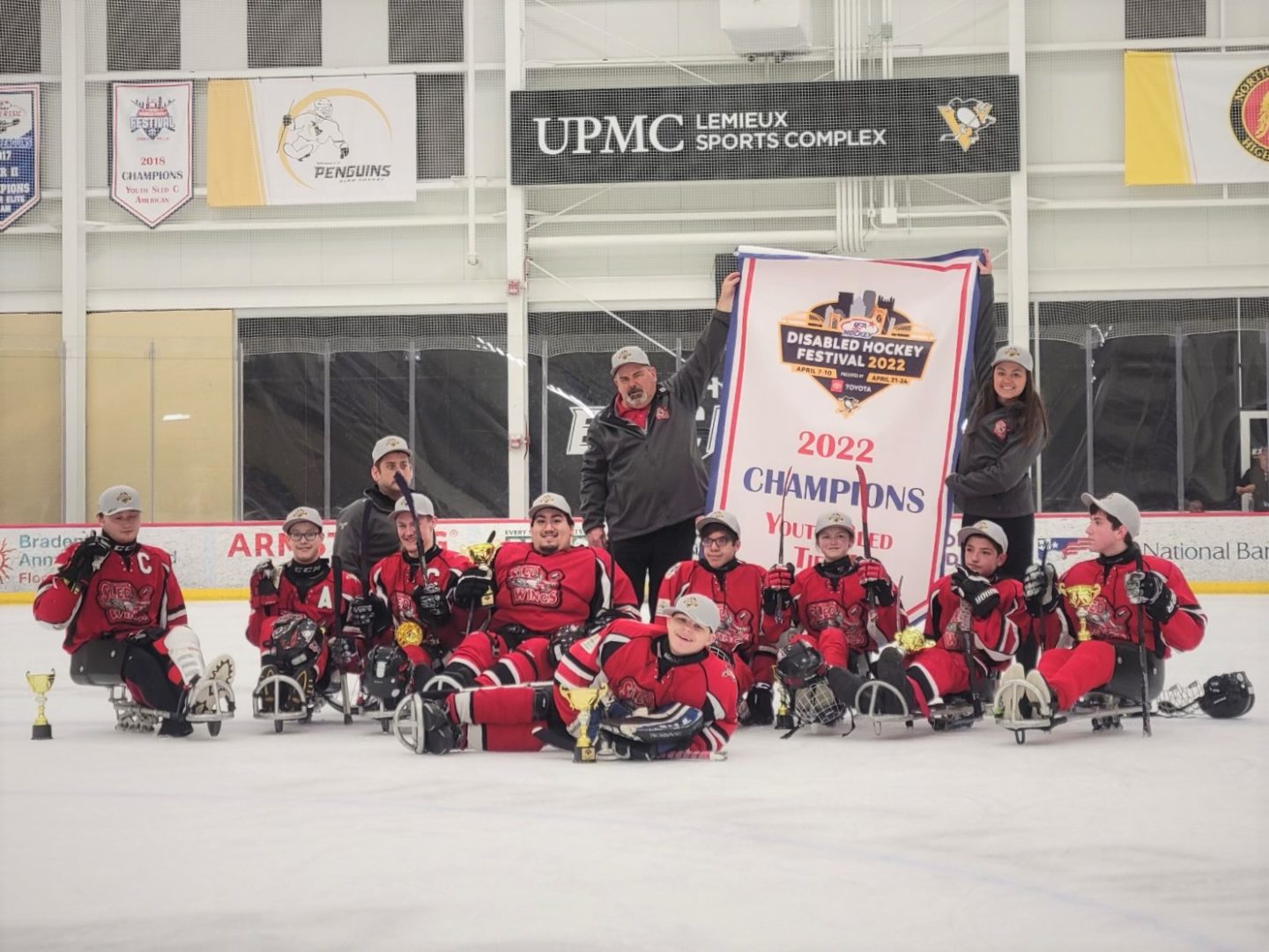Junior Sled Hockey Team Win National Title pose with banner and trophy