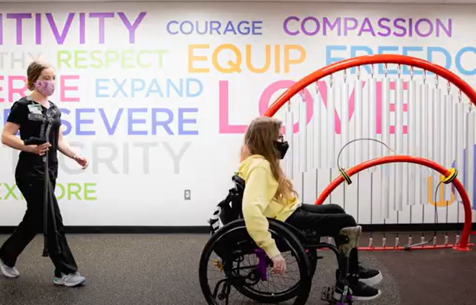 Nurse walking behind a patient in a wheelchair.