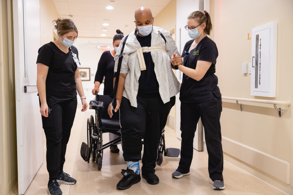 Lavell and his physical therapy team practice walking in the hospital hallway.