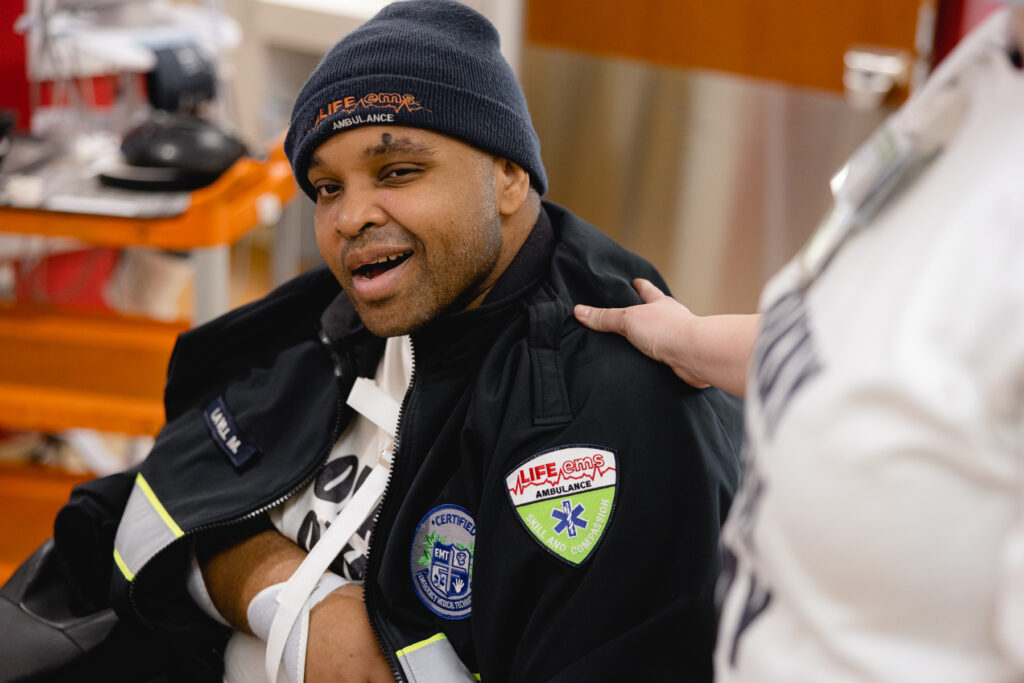 Lavell smiles at camera on his graduation day. He is proudly wearing his Life EMS jacket.