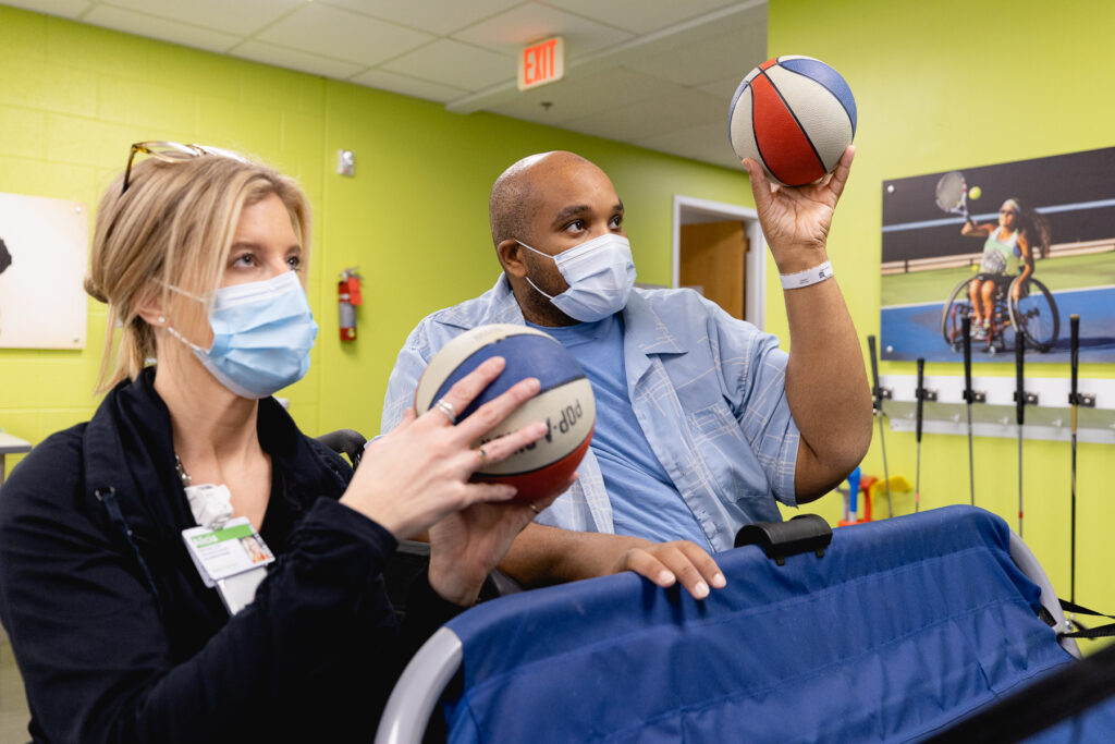 Lavell and his therapist practice shooting basketballs in rec therapy.