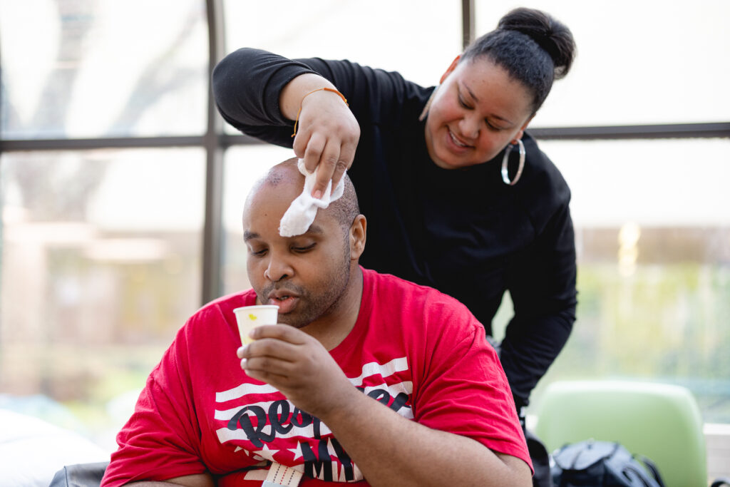 Destiny cares for Lavell as he takes a drink of water during outpatient therapy.