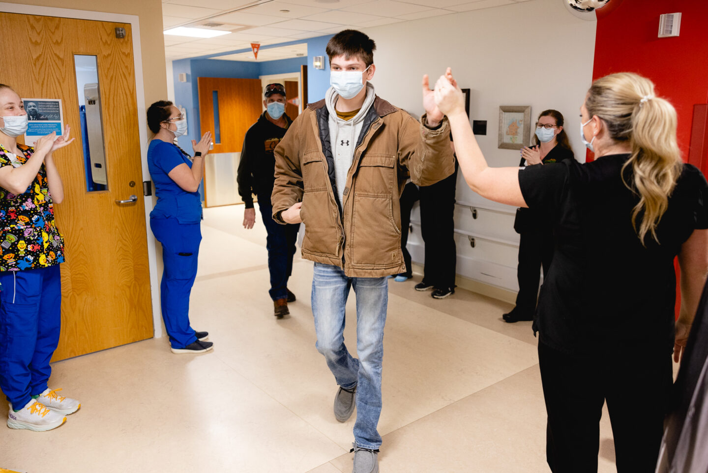 High school boy high fives his nurses on his way home from the hospital.