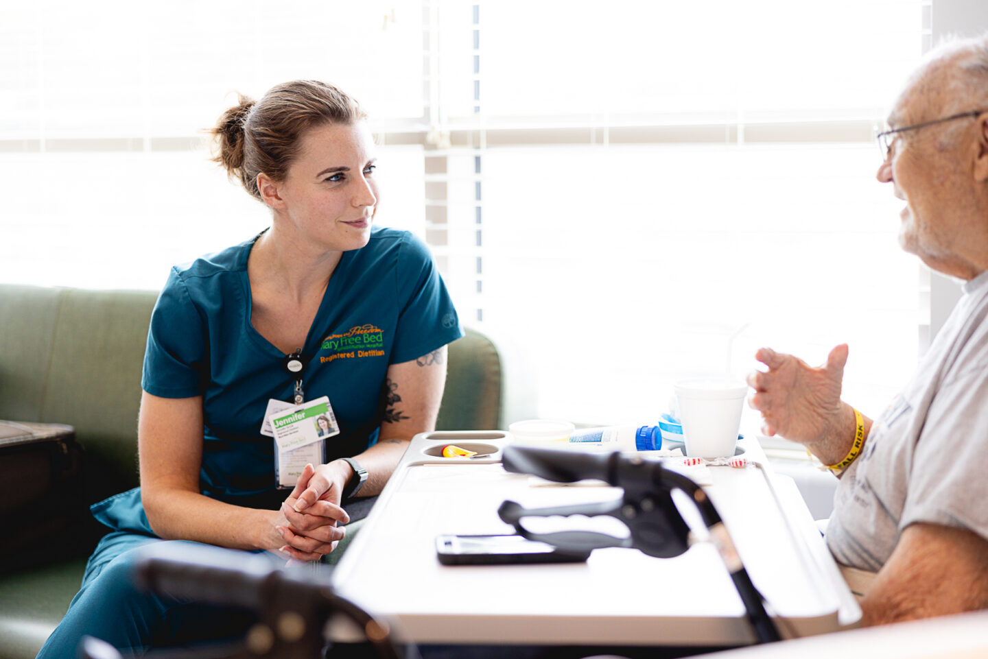 Jenn, a Mary Free Bed Registered dietitian, speaks with a patient in his hospital room