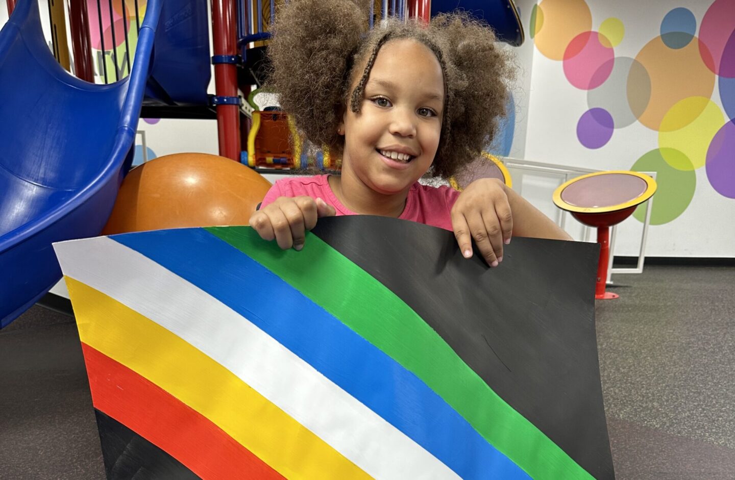 Patient with a disability holds a disability pride month flag during one of her therapy sessions