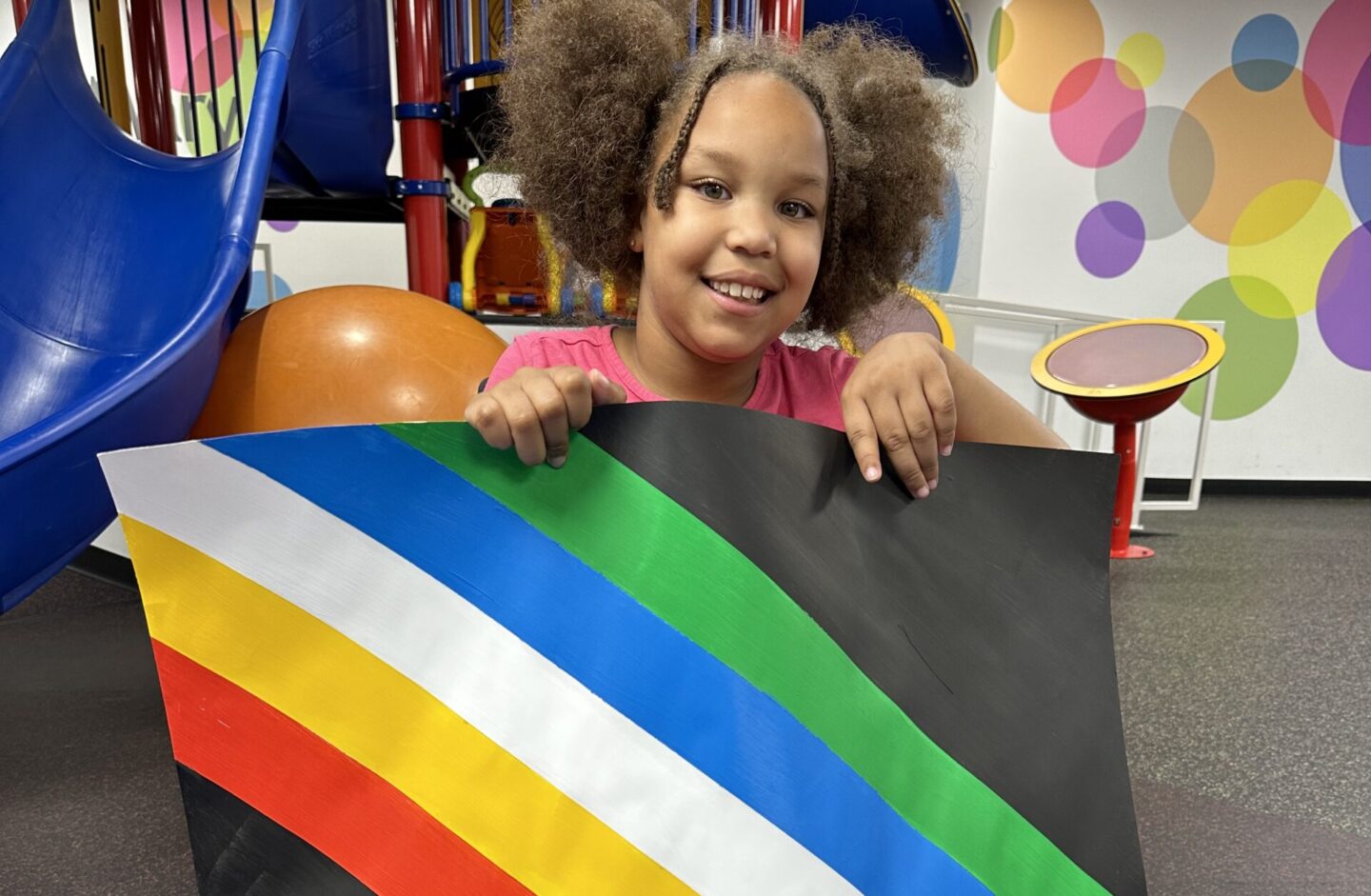 Patient with a disability holds a disability pride month flag during one of their therapy sessions