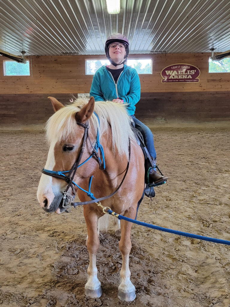 Loralei is sitting on her horse and smiling at the camera