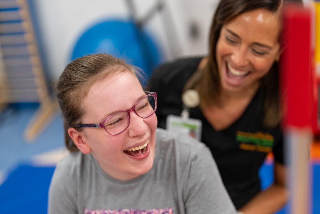 Loralei and her physical therapist laugh during a physical therapy appointment at Mary Free Bed Rehabilitation Hospital