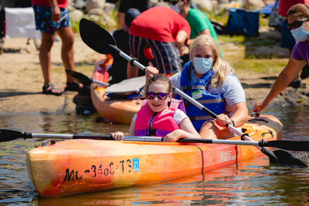 Loralei kayaks with an instructor during the adaptive kayaking clinic with Mary Free Bed wheelchair and adaptive sports.