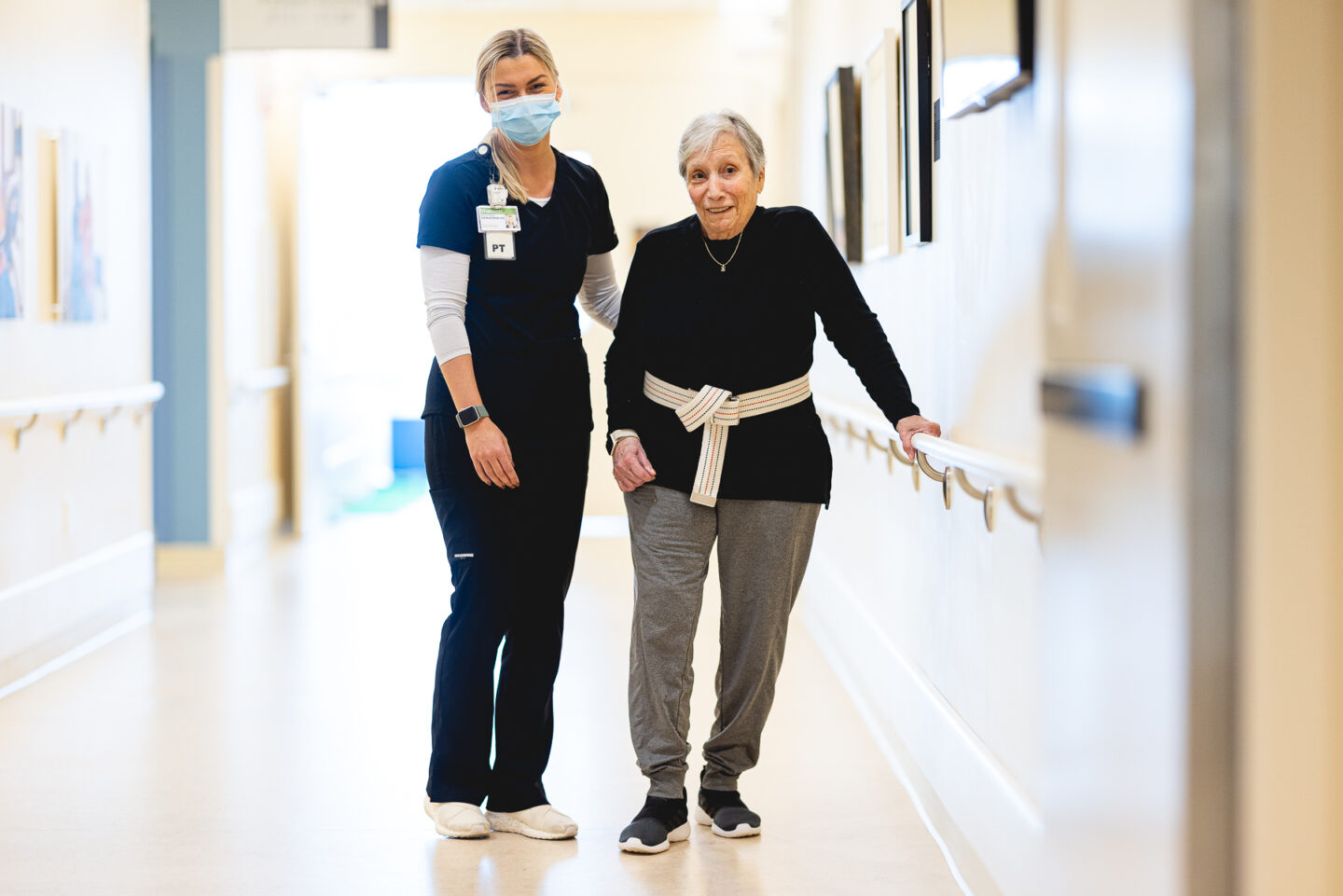 physical therapist working with a patient and smiling in the hall of a rehabilitation hospital