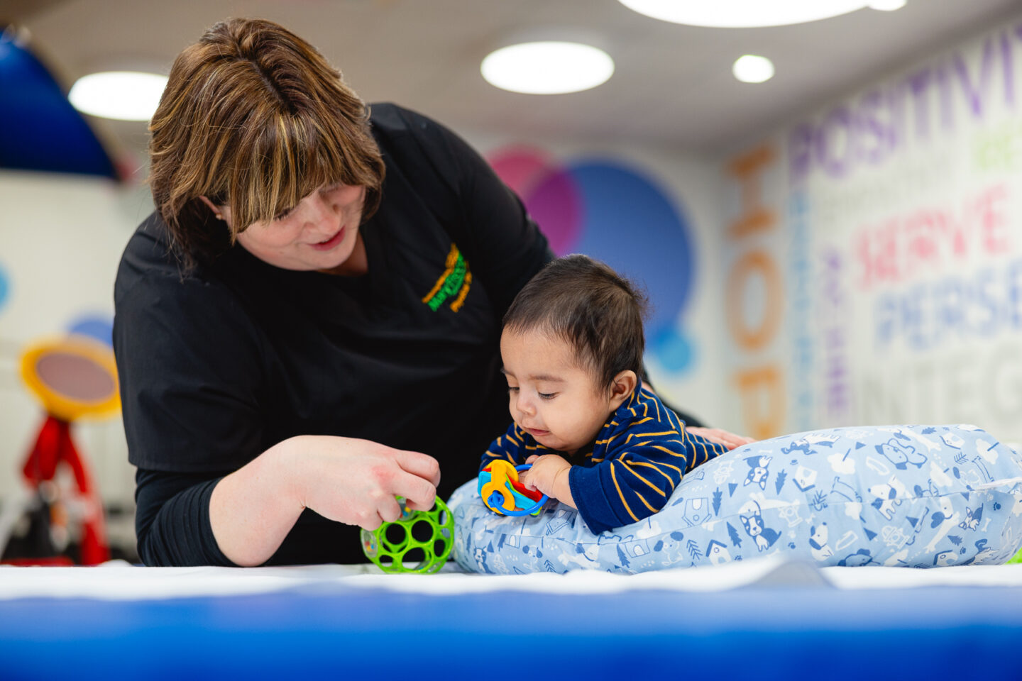 Infant plays with toys while on his tummy