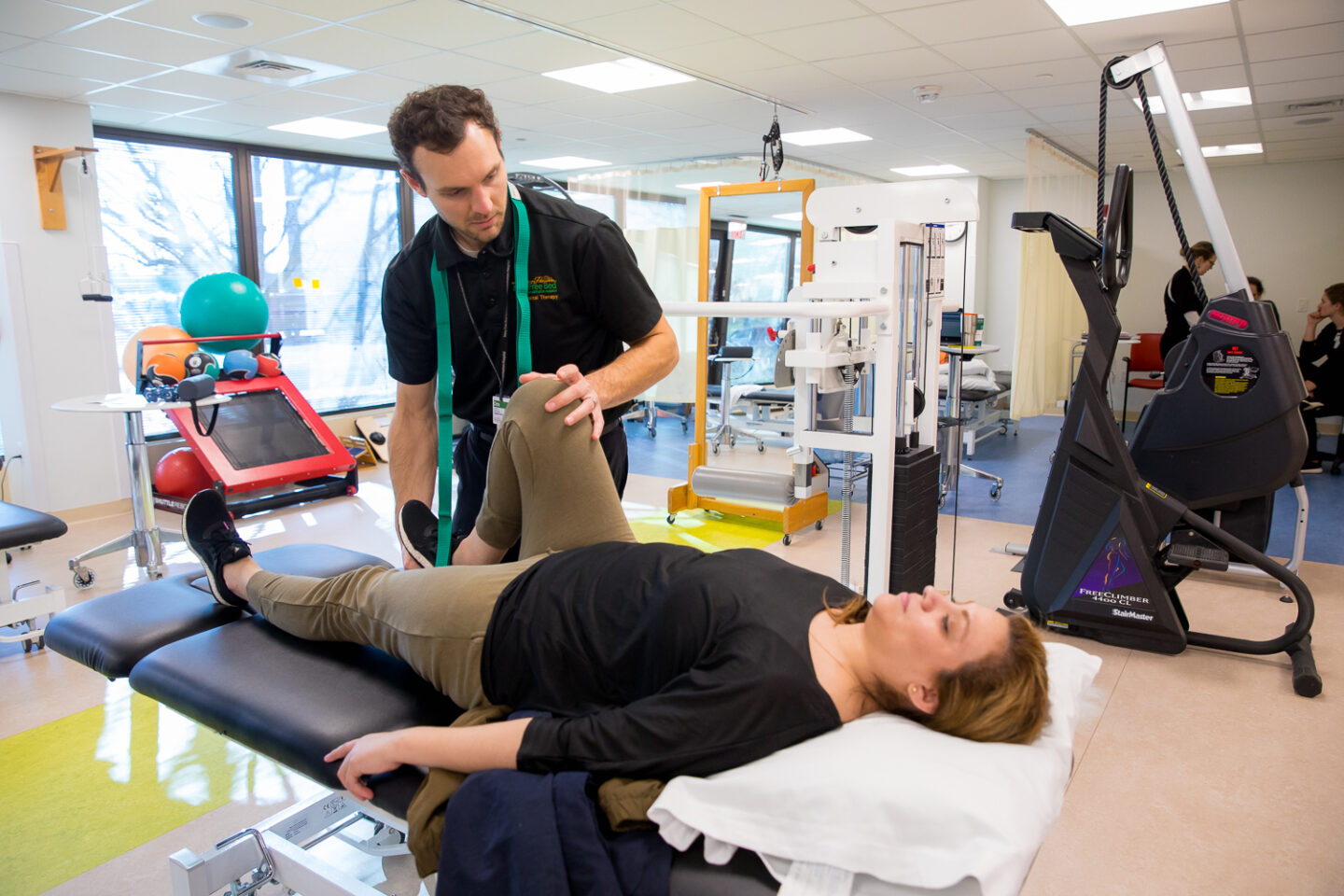 Physical therapist assisting with a leg stretch to help improve a patient