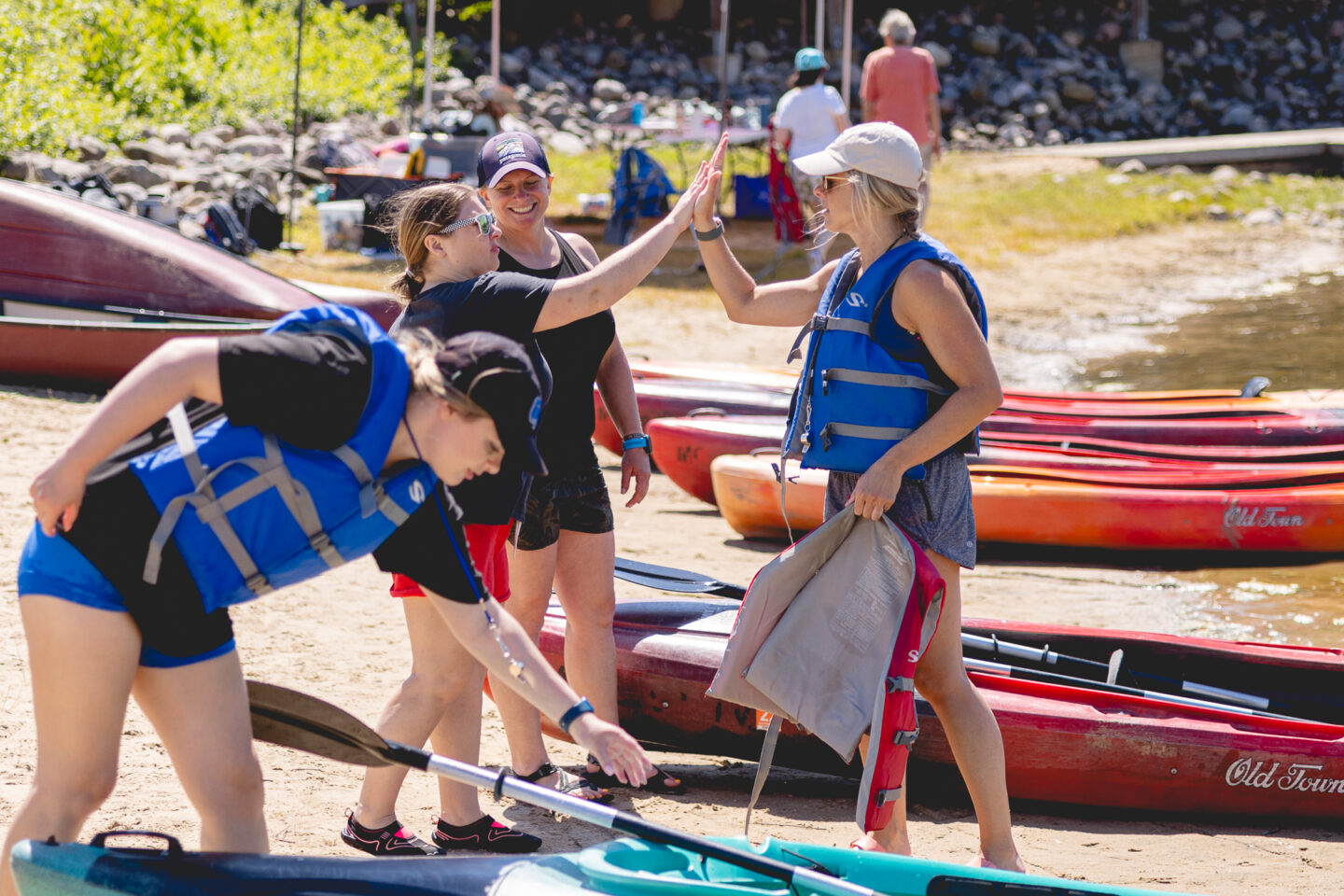 Participants at an adaptive sports clinic high-fiving on the shore after a successful kayaking session at Millennium Park.
