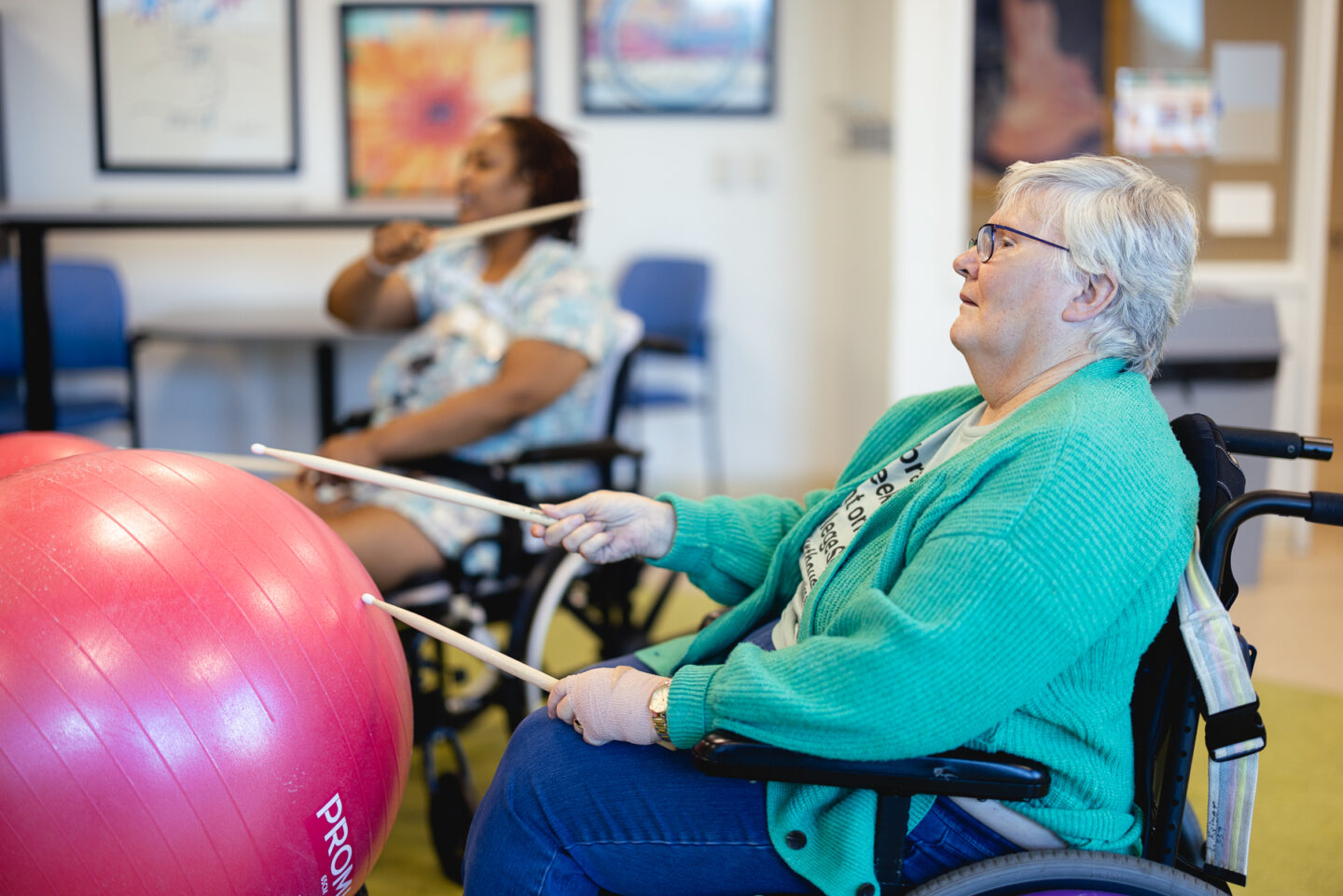 Patients participate in a cardio drumming session with exercise balls and drumsticks.
