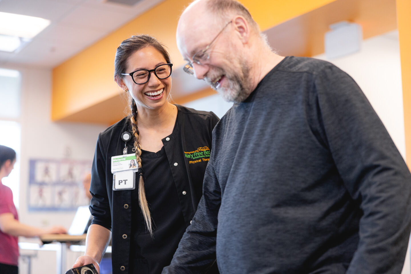 Physical therapist smiling and assisting a patient during a fall prevention session.