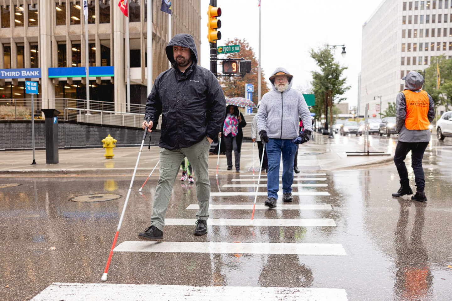 people walking through a city downtown using white canes as a tool