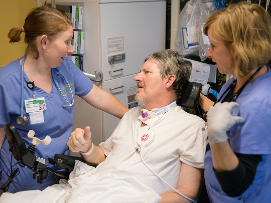 Two doctors help a patient with respiratory therapy.