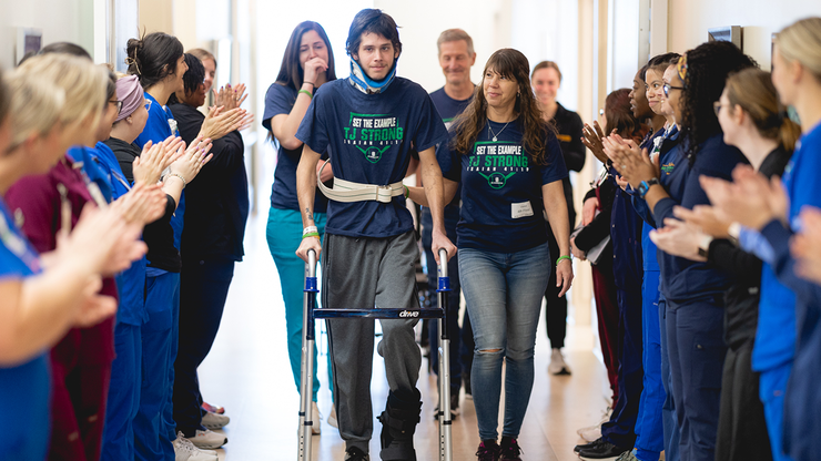 Patient with a walker being cheered on by Mary Free Bed professionals.