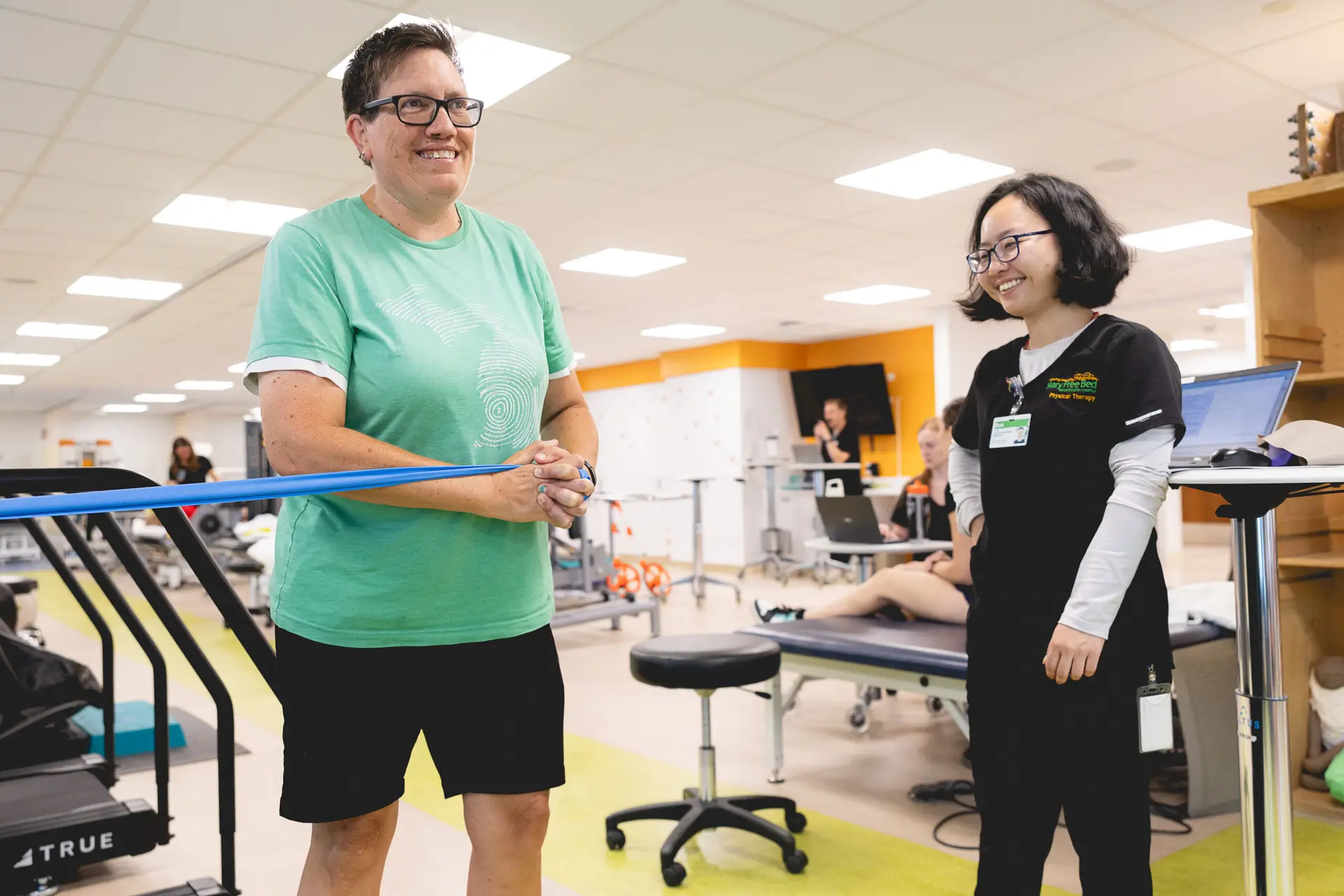 a patient participating in physical therapy exercises while a therapist watches.