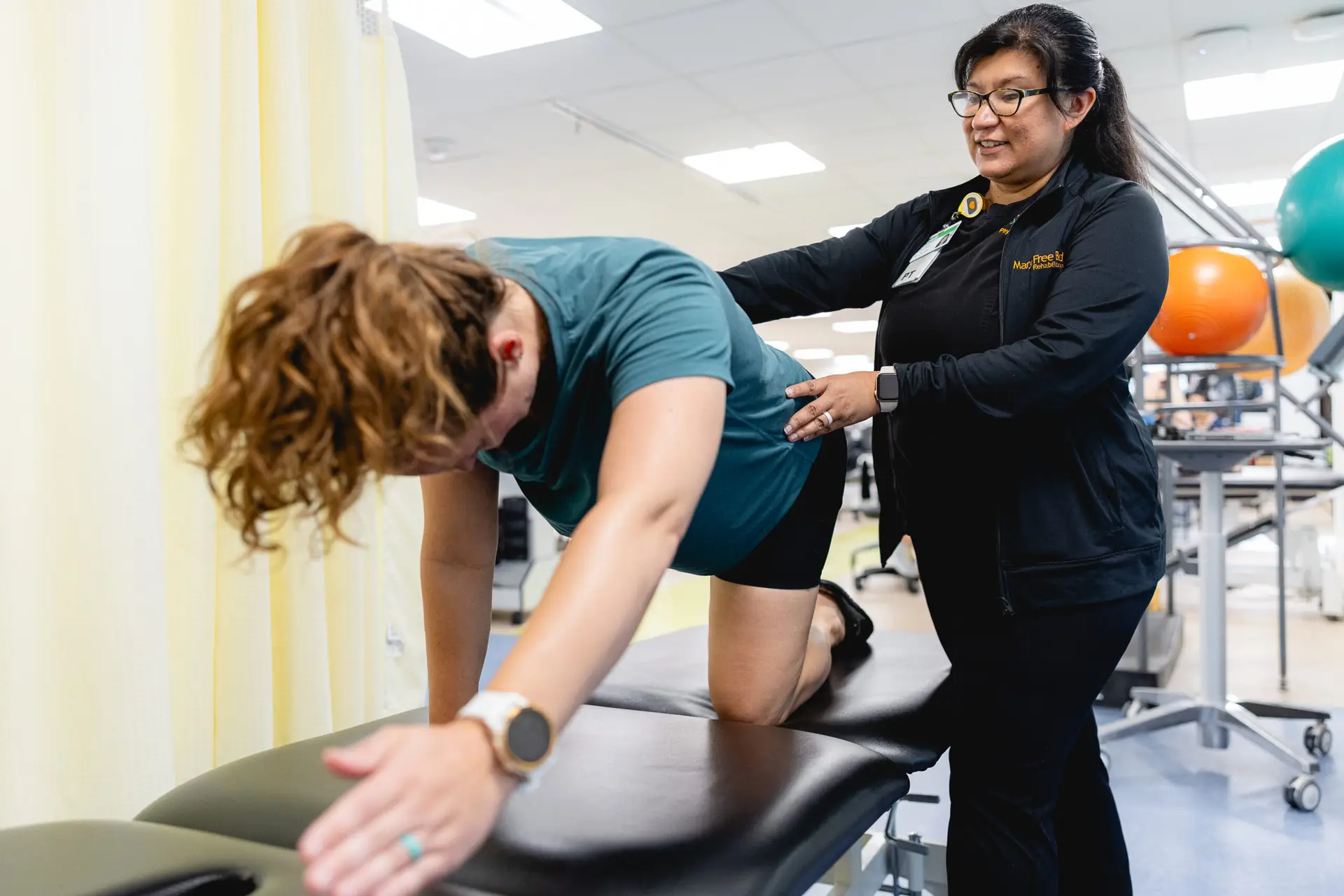 A Physical Therapist assisting a patient with a therapy exercise
