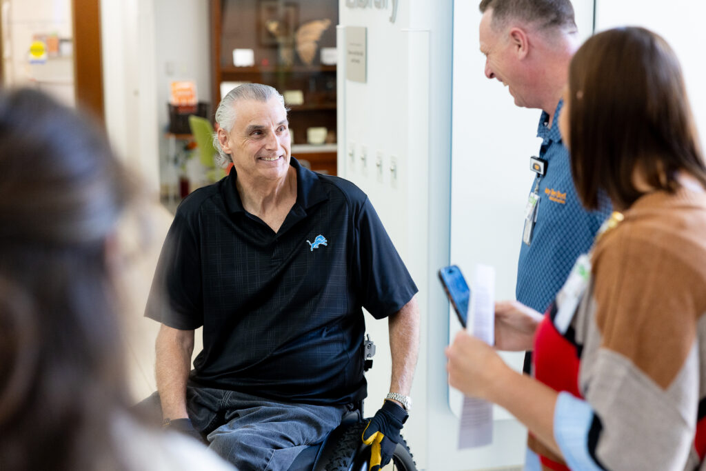 Mike Utley shown smiling with Mary Free Bed Therapists
